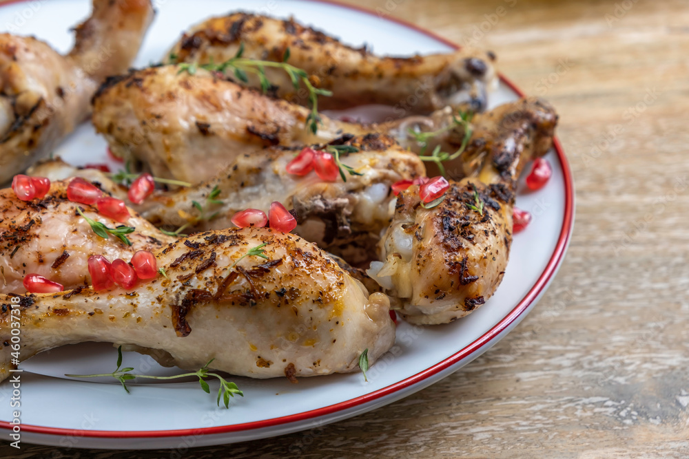 Baked chicken legs with pomegranate seeds and fresh thyme for Jewish holiday Rosh Hashanah.
