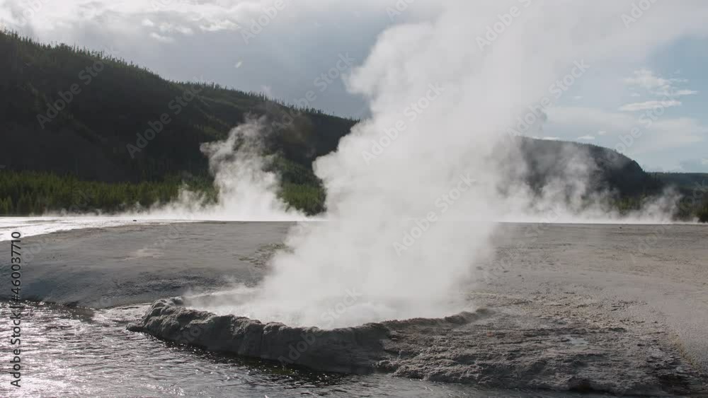 Scenic hot geyser eruption on sunny summer day in Yellowstone National Park 4K footage. Hot boiling water splashing with hot thick steam raising up in air in ancient volcano caldera in North America Scenic hot geyser eruption on sunny summer day in Yellowstone National Park 4K footage. Hot boiling water splashing with hot thick steam raising up in air in ancient volcano caldera in North America
