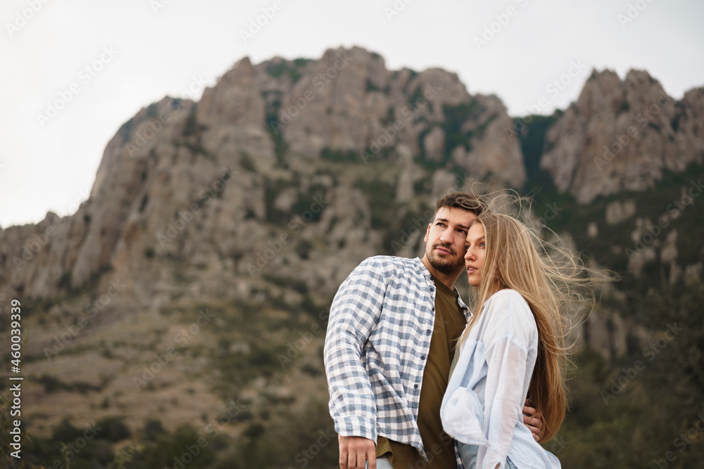 Happy loving couple hiking and hugging in mountains