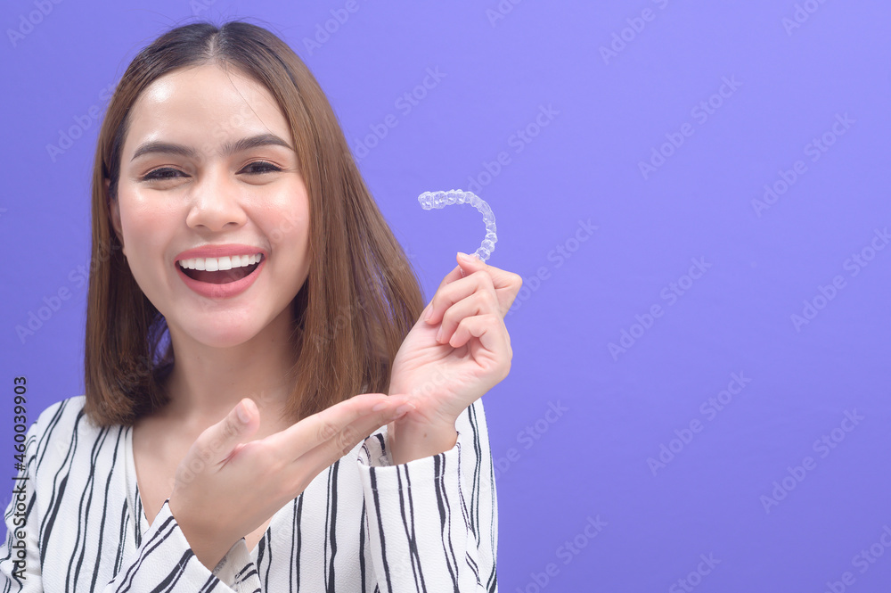 Young smiling woman holding invisalign braces in studio, dental healthcare and Orthodontic concept.. Young smiling woman holding invisalign braces in studio, dental healthcare and Orthodontic concept..