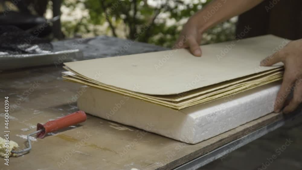 Man's hands placing wooden planks on white shaping block to build DIY skateboard on workbench in workshop. Close up slider pan left to right Man's hands placing wooden planks on white shaping block to build DIY skateboard on workbench in workshop. Close up slider pan left to right