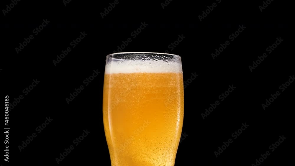 Lager Beer closeup. Cold beer isolated on matte black background. Glass of beer with water drops and bubble Lager Beer closeup. Cold beer isolated on matte black background. Glass of beer with water drops and bubble