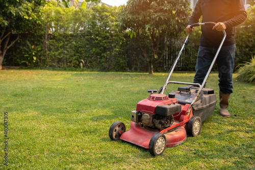 Garden work on the care of the lawn. A man mows the lawn using an electric pushing lawn mower..