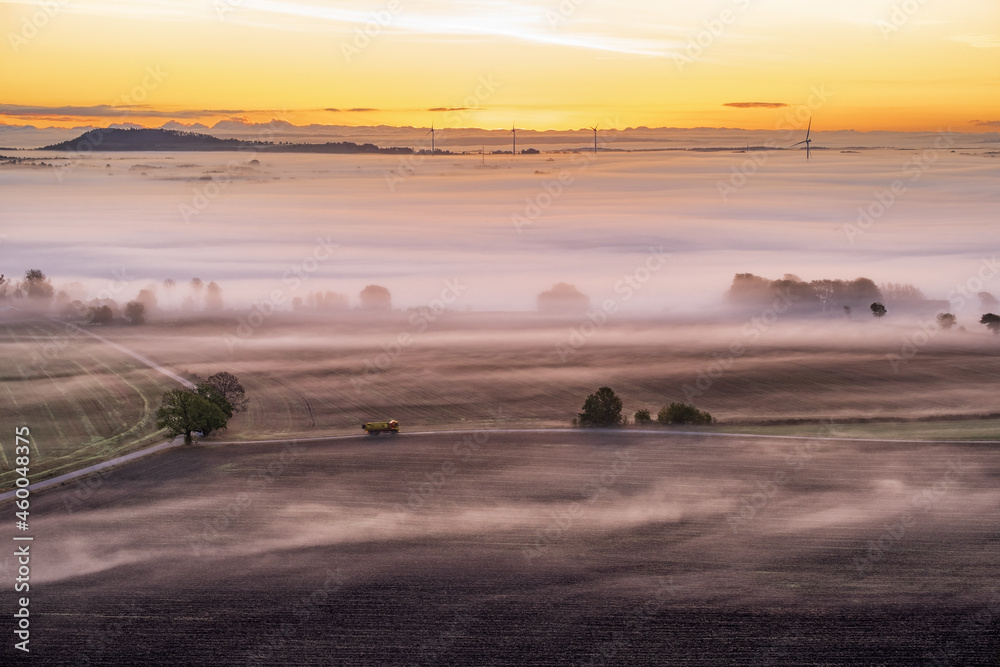 Fototapeta premium Truck driving on a country road at sunrise with mist