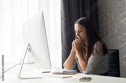 Upset young female employee worrying about project, frustrated woman sitting at the desk in front of PC with eyes closed lost in thought, full of doubt