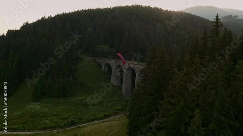 Dynamic aerial footage of a paraglider flying over a beautiful old bridge. Chmarocsky viaduct in Slovakia, Central Europe. photo