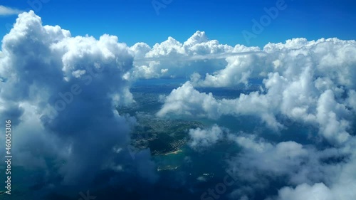 美しいサンゴ礁に囲まれた沖縄と南国らしいたくさんの積乱雲の中を飛ぶ飛行機からの眺め