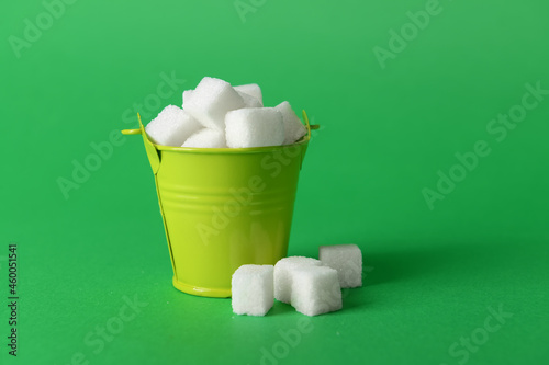 Bucket with sweet sugar on color background