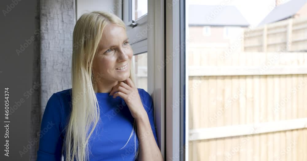 Smiling blond woman looking out of window Smiling blond woman looking out of window