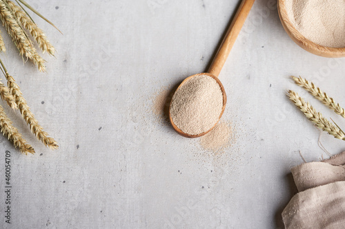 Dry yeast in wooden spoon and bowl on tabel with wheat 
