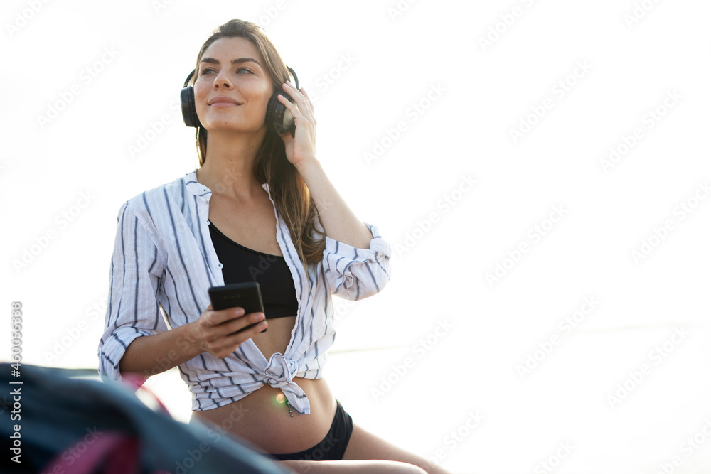 Naklejka premium Happy young woman relaxing on the sandy beach. Beautiful woman listening the music