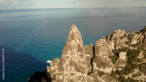 Aerial drone video of coastline and beach of Cala Goloritzé with impressive rock formation at the turquoise water of the mediterranean sea during sunset, Italy