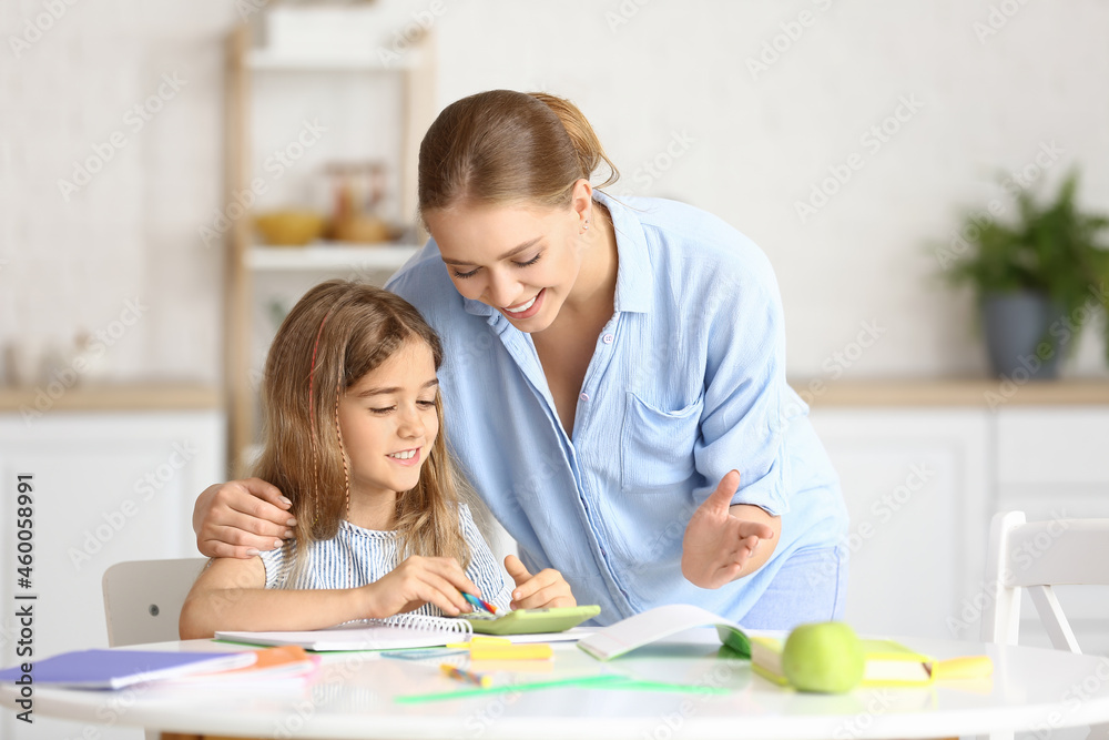 Little girl with her mother doing lessons at home