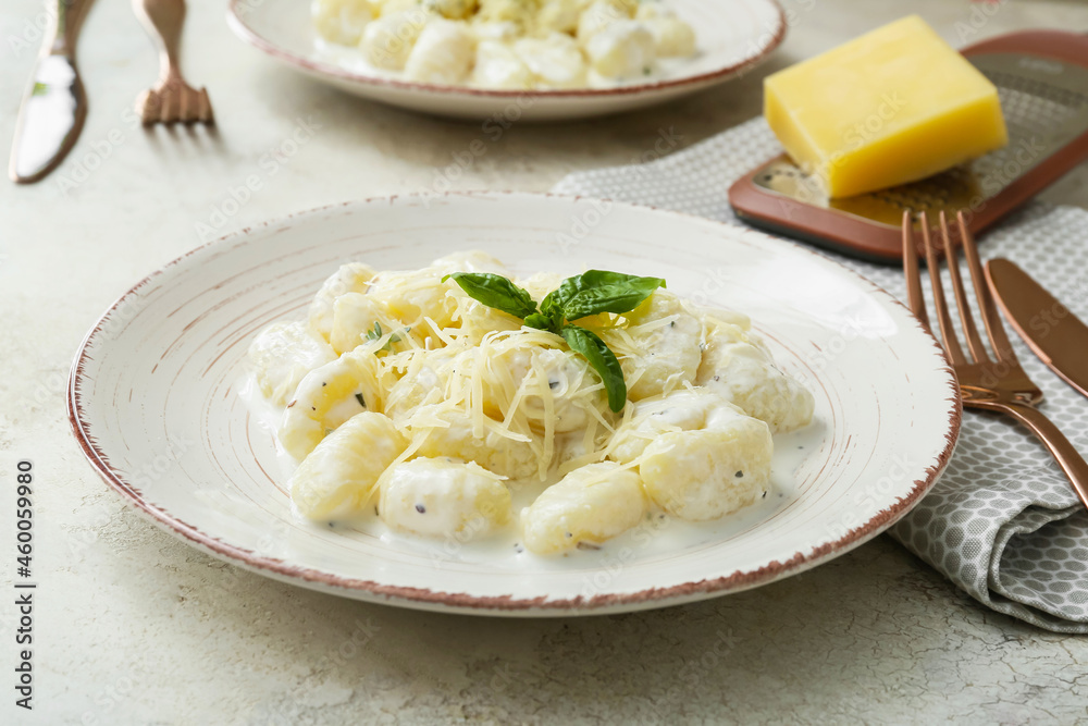 Plate of delicious gnocchi with creamy sauce on light background