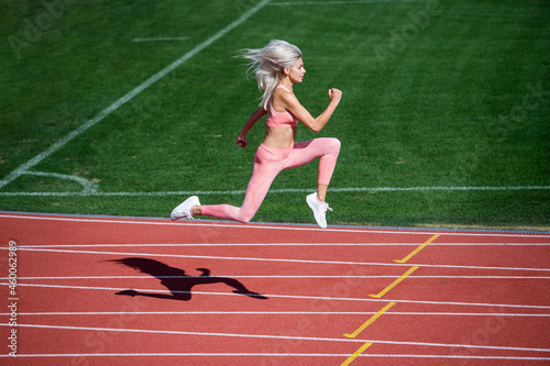 sport woman in sportswear sprinting on stadium running track before training fitness, active lifestyle