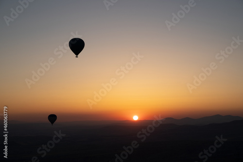 hot air balloon silhouettes with sun rising over the mountains