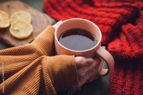 Photos Cup of hot in woman's hands holding it over wooden autumn background with leaves and plaid Top view