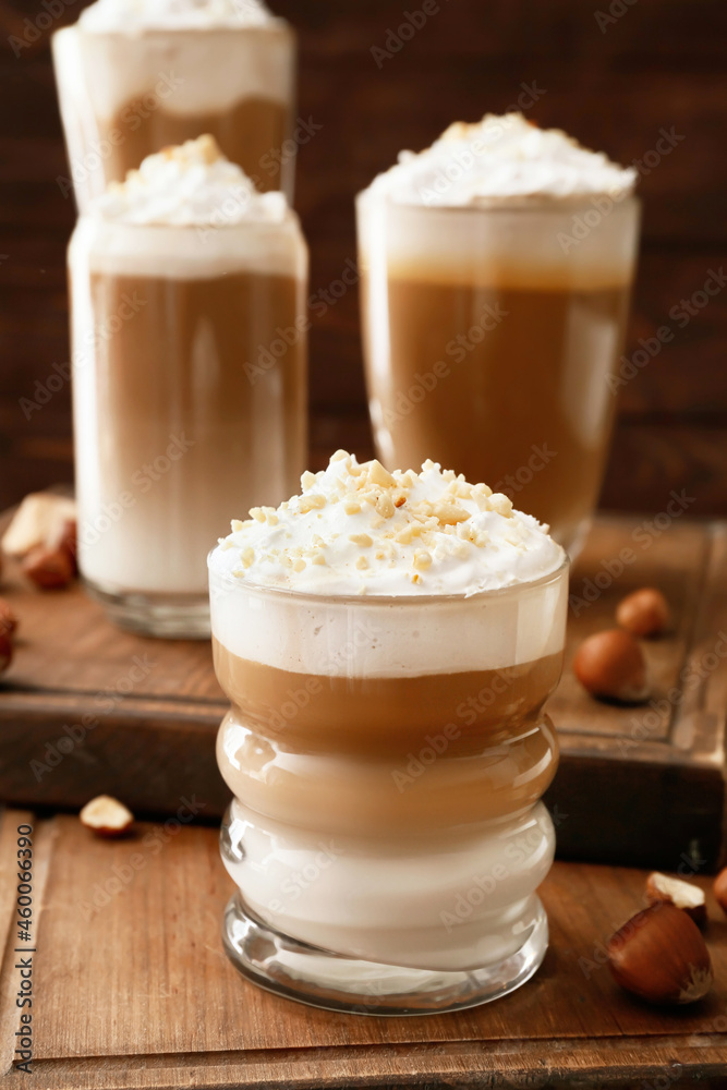 Glasses of tasty latte with nuts on wooden background Glasses of tasty latte with nuts on wooden background