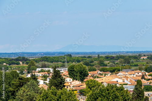 Aigues-Mortes medieval town red tailed rooftops and Mont Ventoux silhouette on the background, France © nomadkate