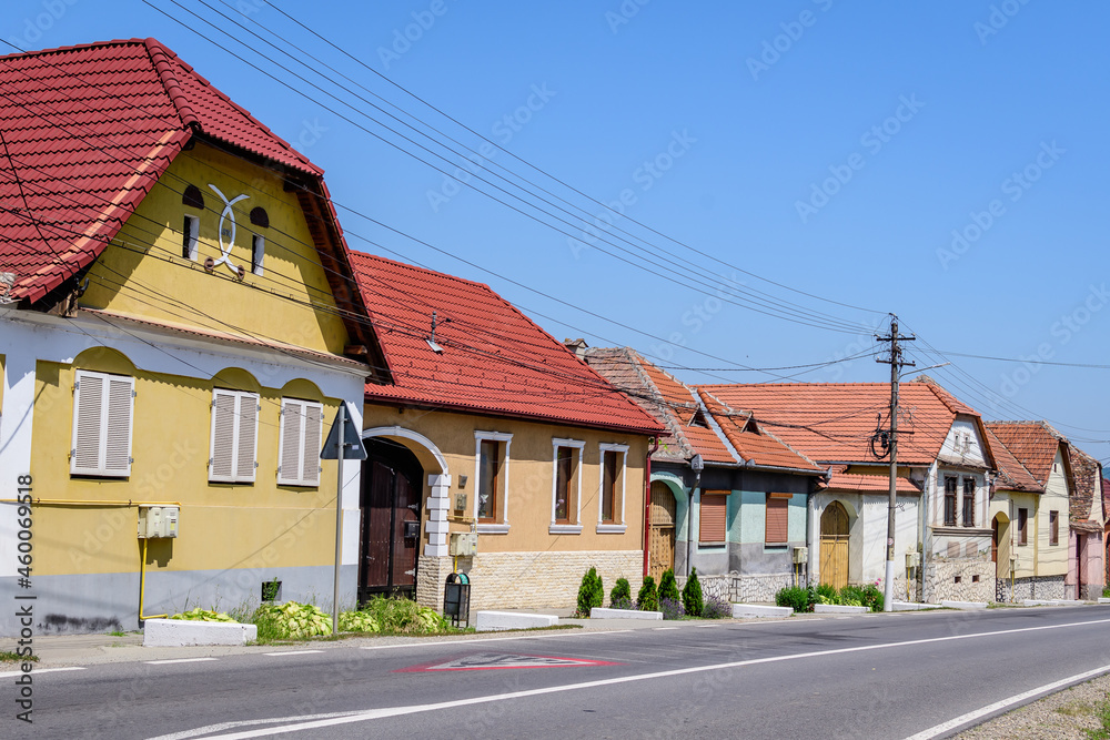 Colorful old houses near the fortitied church in Axente Sever village in Sibiu county, in Transylvania (Transilvania) region of Romania, in a sunny summer day