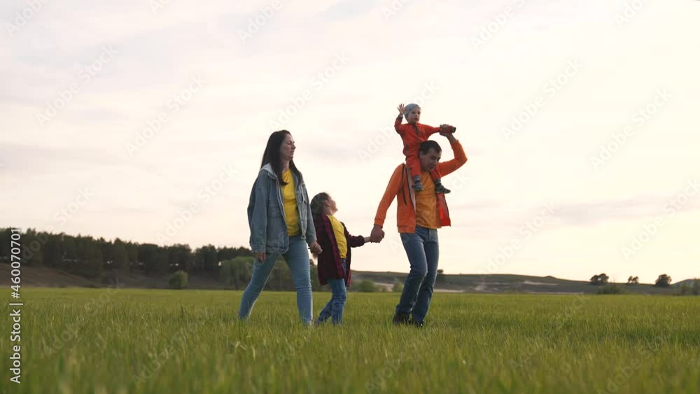Happy family is walking on green grass. Mom dad and girl with toddler in park at sunset. Happy family walking in park at sunset. Mom dad girl and baby on green grass. Happy family concept at sunset Happy family is walking on green grass. Mom dad and girl with toddler in park at sunset. Happy family walking in park at sunset. Mom dad girl and baby on green grass. Happy family concept at sunset