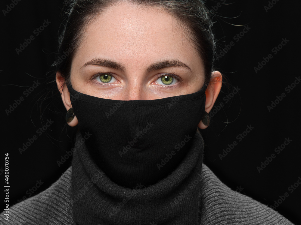 brunette girl in a black COVID mask on a black background