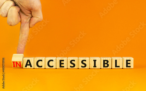 Accessible or inaccessible symbol. Businessman turns a wooden cube, changes the word Inaccessible to Accessible. Beautiful orange background, copy space. Business, accessible or inaccessible concept. photo