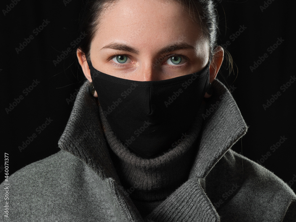 brunette girl in a black COVID mask on a black background brunette girl in a black COVID mask on a black background