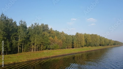 Picturesque river landscape with green trees in early autumn. View from the ship's porthole