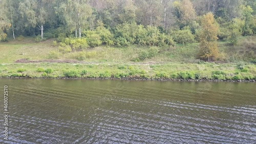 Picturesque river landscape with green trees in early autumn. View from the ship's porthole