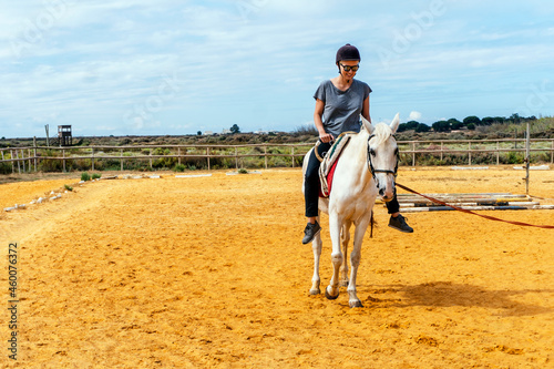 A woman taking horse riding lessons in a paddock