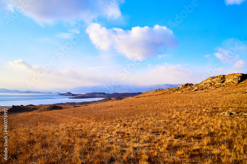 Nature landscape with golden field, wather, hills and blue sky with white clouds in a day or a evening