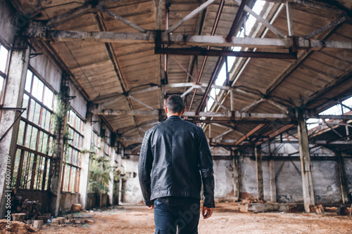 Handsome Man in Black Jacket in Dark Empty Abandoned Factory Hall 