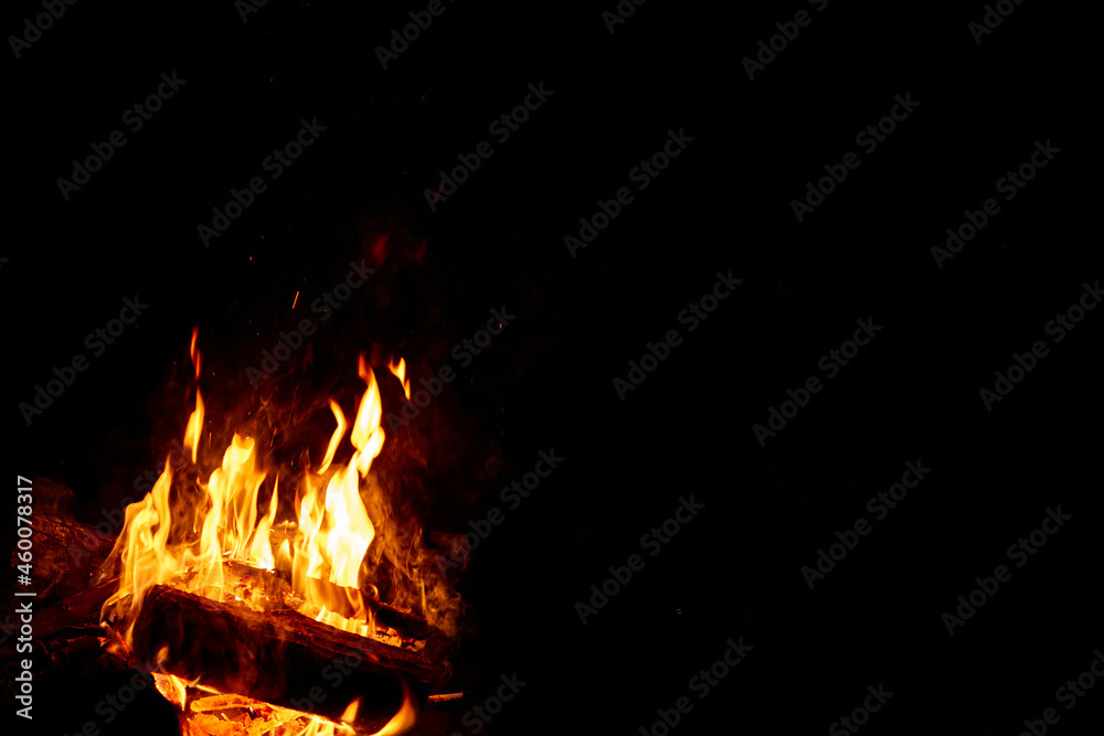 Fire or campfire lit. High flames with sparks. Half of the image in black with space for writing. Photo for design, wallpaper, text. Fire or campfire lit. High flames with sparks. Half of the image in black with space for writing. Photo for design, wallpaper, text.