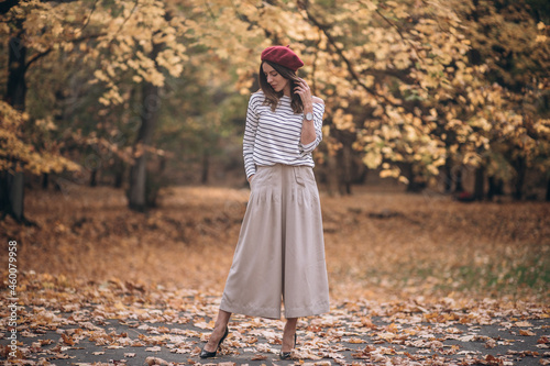Portrait of brunette woman in autumn in the park. French style. Woman in beret and striped blouse
