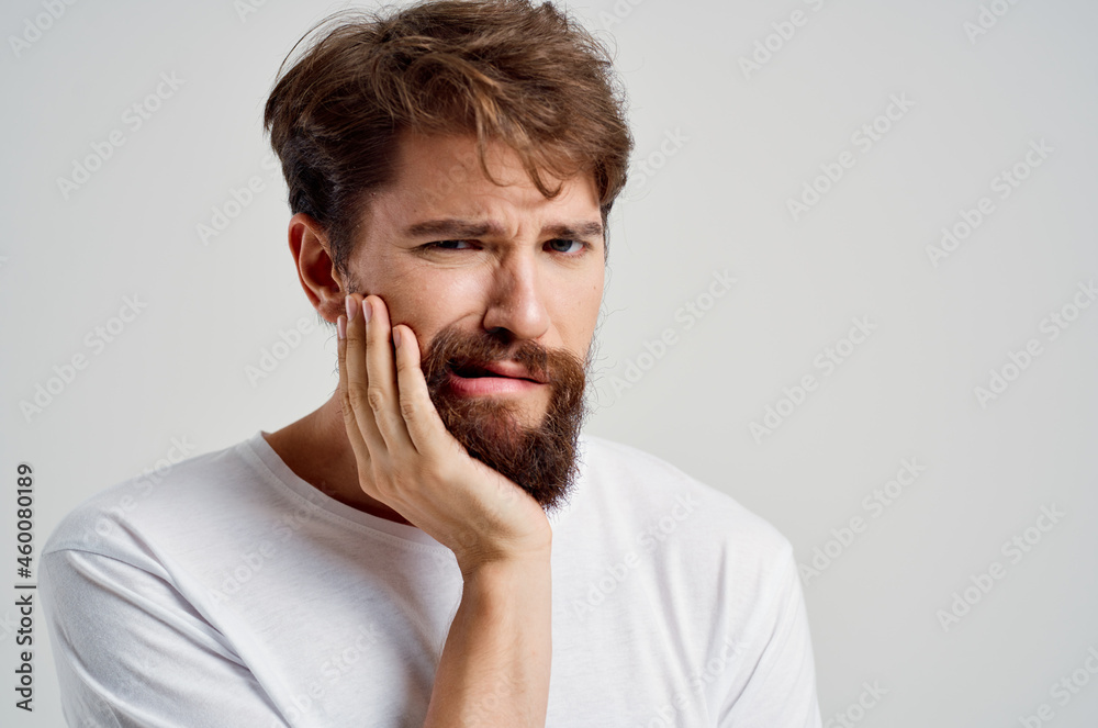 bearded man holding on to face pain in teeth isolated background