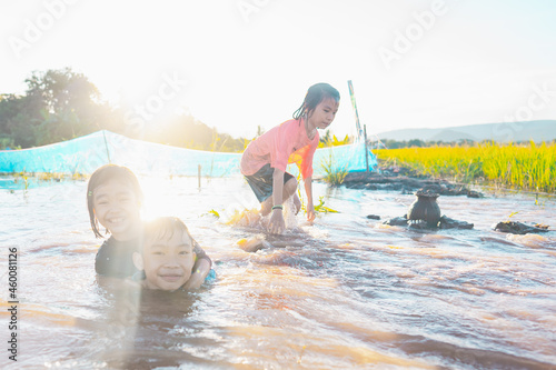 Kids playing and swim in nature pond and flowing water on sunlight background in rural or countryside