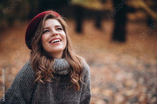 Portrait of a joyful young woman enjoying in the autumn park. beautiful blonde girl in autumn red beret and gray sweater. Relax in nature