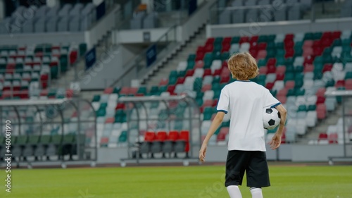 Portarit of Caucasian pre teen kid boy entering the field of huge soccer stadium, holding a ball, dreaming of becoming professional player, soccer star © supamotion