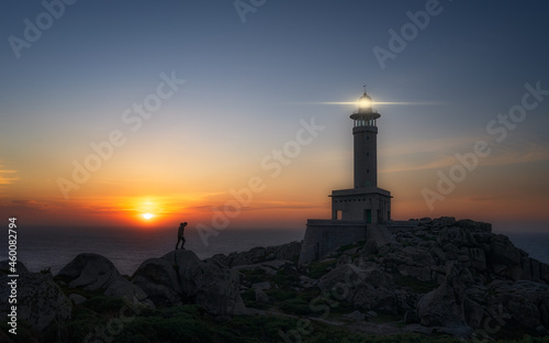 lighthouse at sunset with a man taking care of the next step