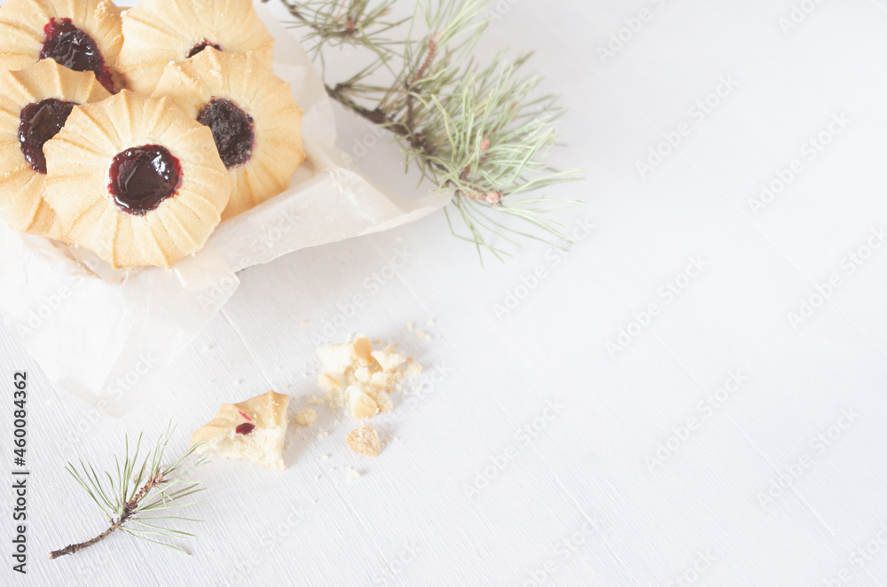 Sweet traditional christmas crumbly biscuits with jam on white wood table with green pine branches, copy space, top view.