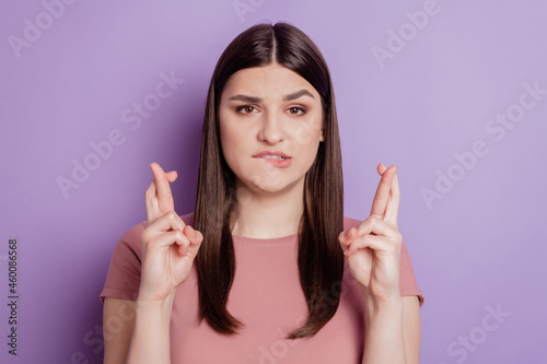 Portrait of pertty coquette hopeful lady hold fingers crossed bite lip plead wish on purple background