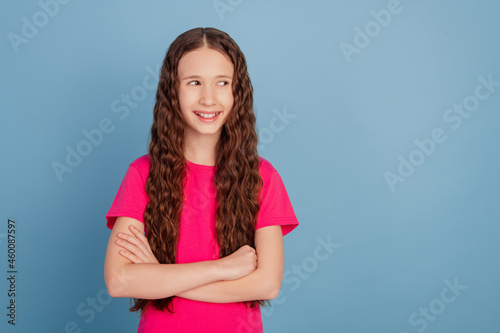 Portrait of successful little lady folded hands look side empty space on blue background
