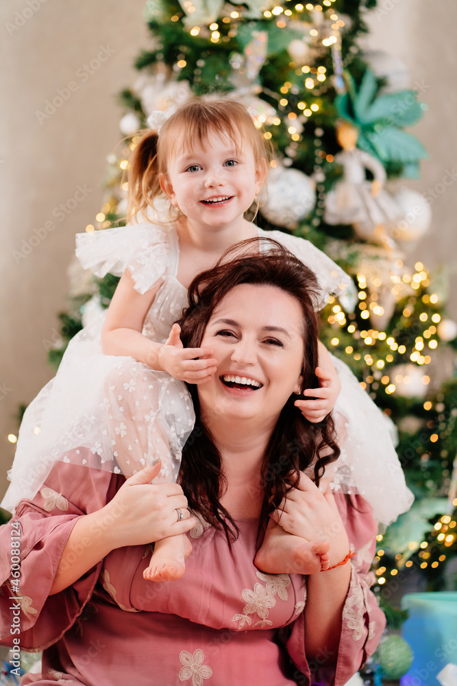 mom and daughter play at the Christmas tree. mom and daughter play at the Christmas tree.
