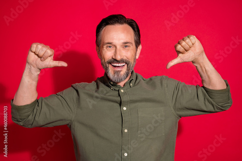 Photo of funny mature brunet man point himself wear khaki shirt isolated on red color background