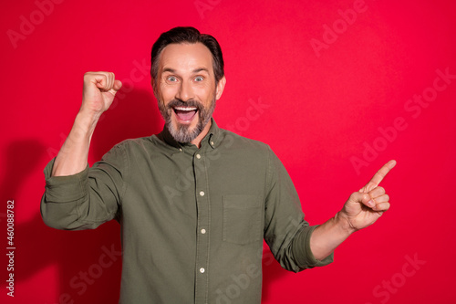 Photo portrait man smiling pointing blank space gesturing like winner isolated bright red color background