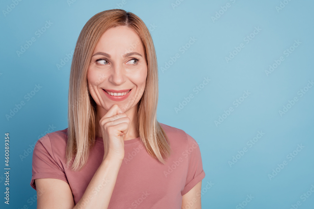 Closeup photo of attractive young woman hand touch chin smile dream look empty space isolated blue color background Closeup photo of attractive young woman hand touch chin smile dream look empty space isolated blue color background