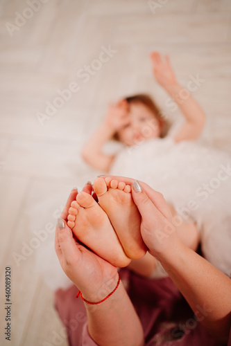 mom holds children s legs in her hands. foot care. 