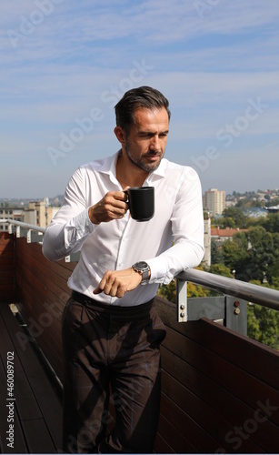 Przystojny brunet w białej koszuli podczas porannej kawy przed wyjściem do pracy.