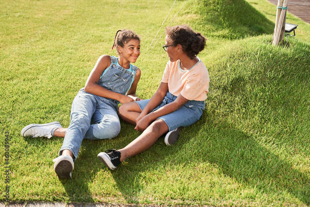 Little black girlfriends resting on green grass Little black girlfriends resting on green grass